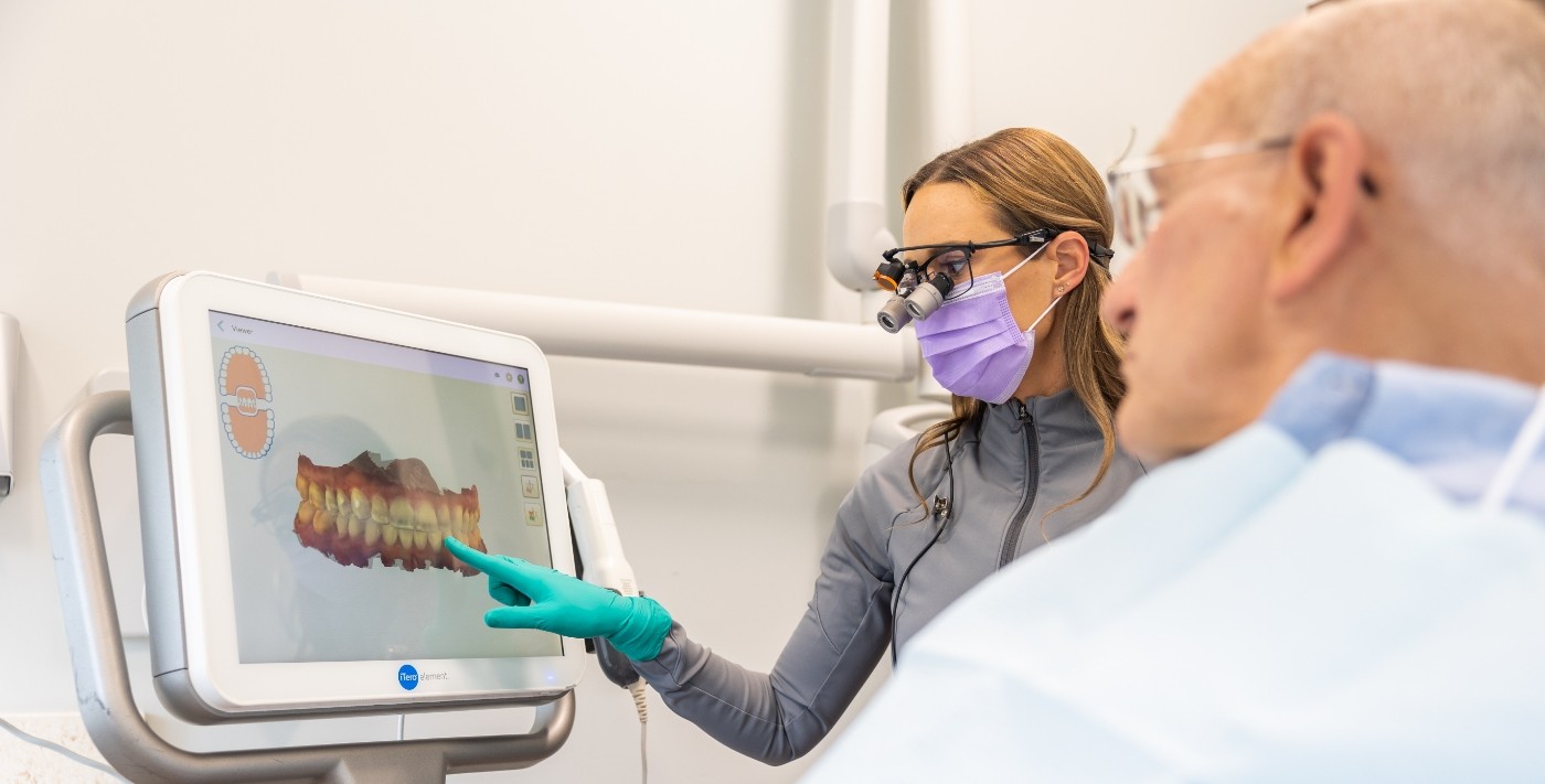 Dentist showing a patient digital scans of their teeth on computer monitor