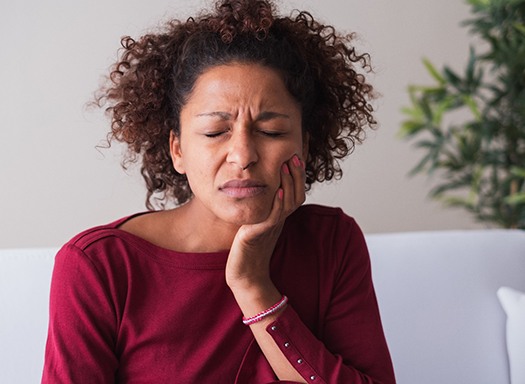 Woman with toothache sitting on couch at home