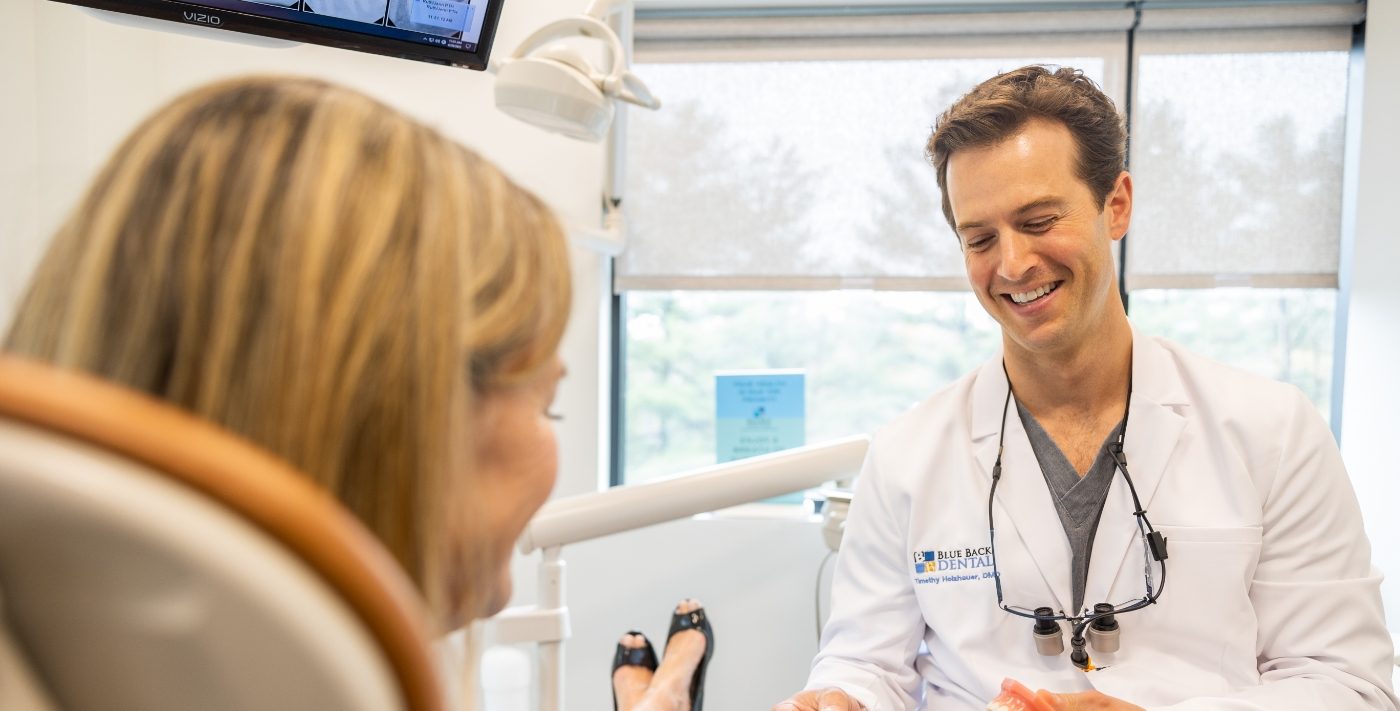 Smiling dentist showing a patient an orthodontic aligner