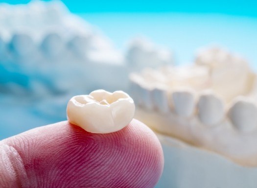 Dental crown resting on finger